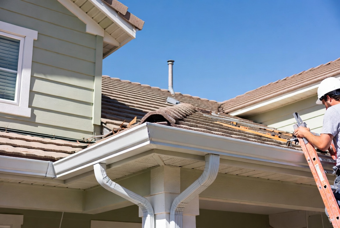 Seamless white aluminum gutters being installed on modern home roofline